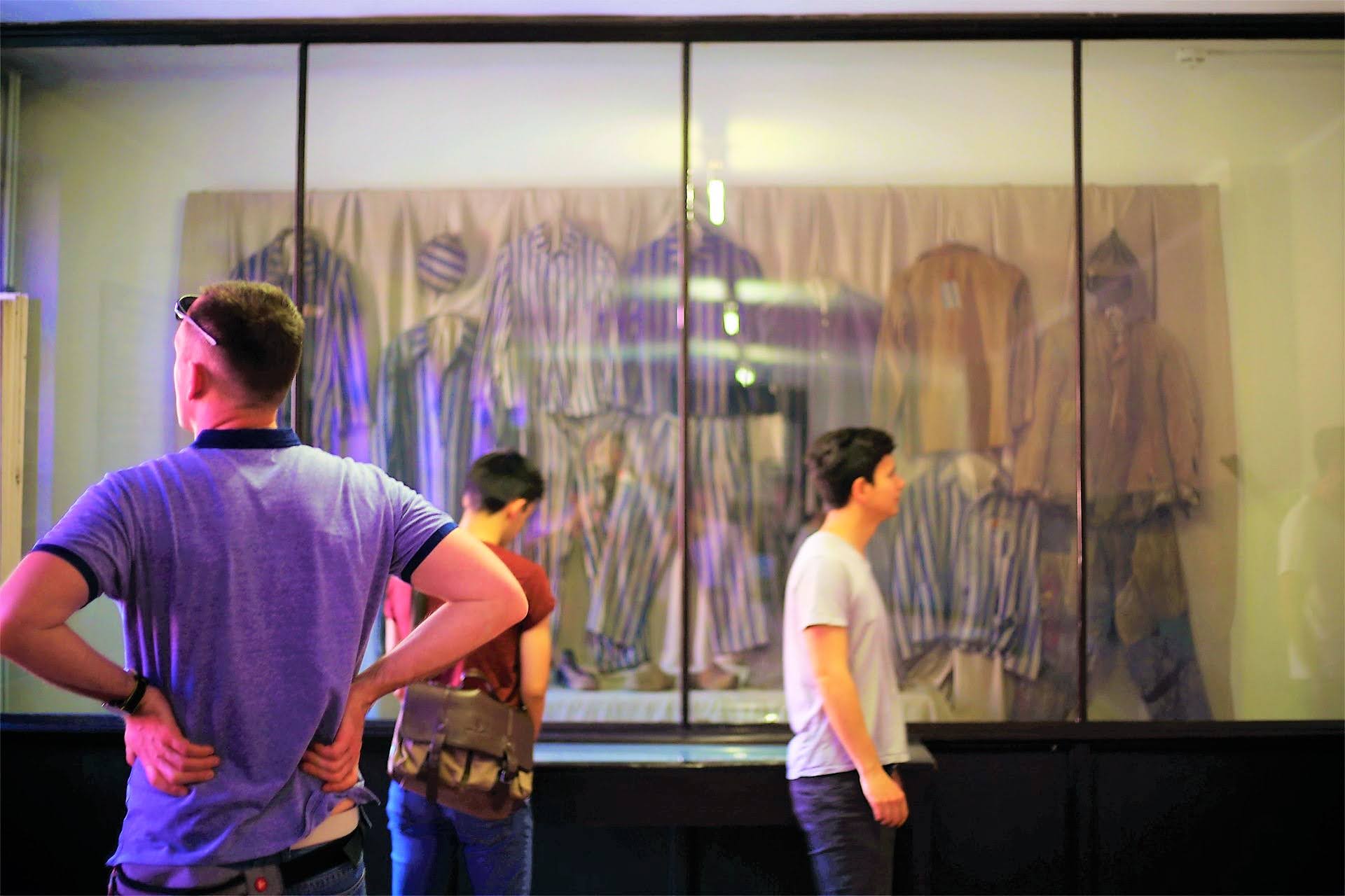 Visitors observing display of prisoner striped uniforms