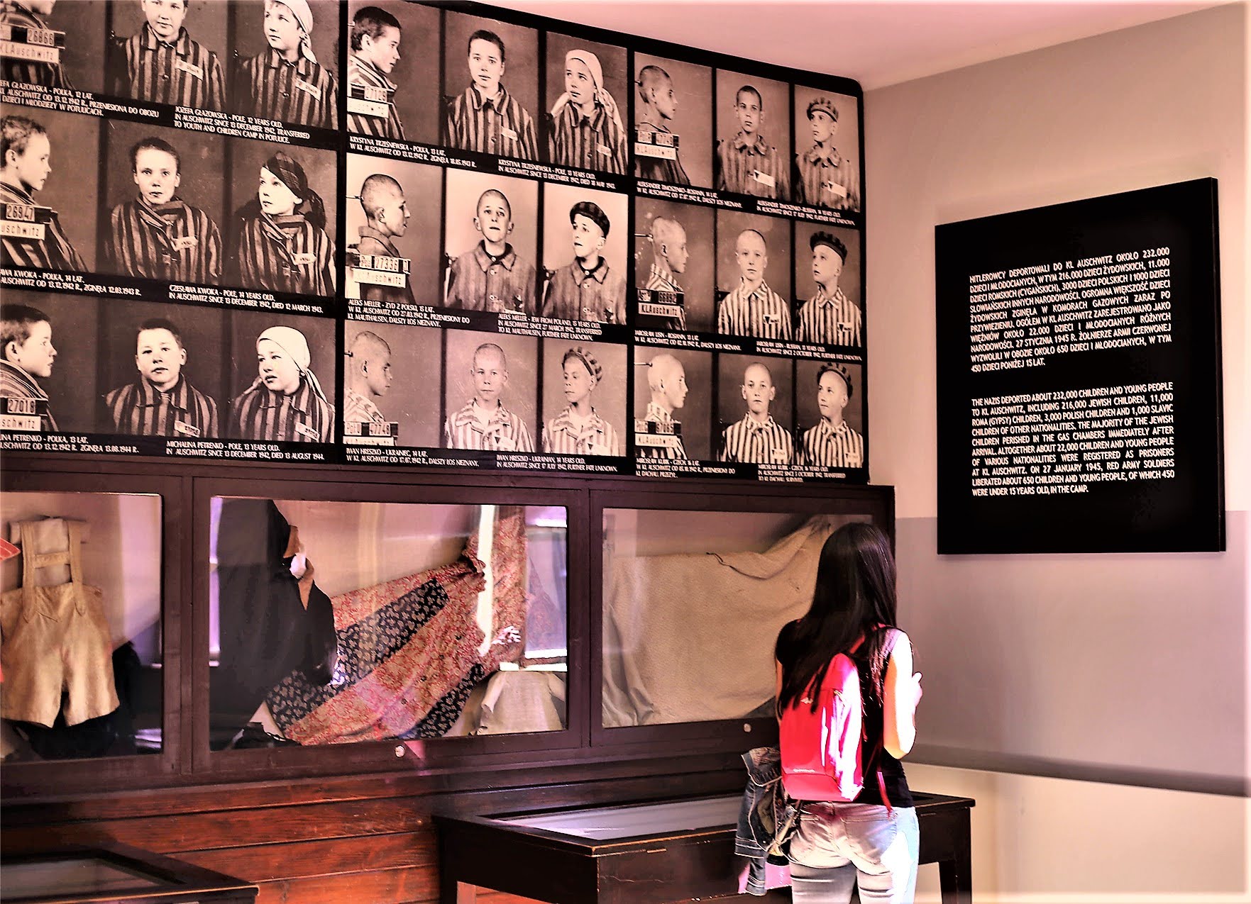 Memorial wall of child prisoner photographs with historical text panel