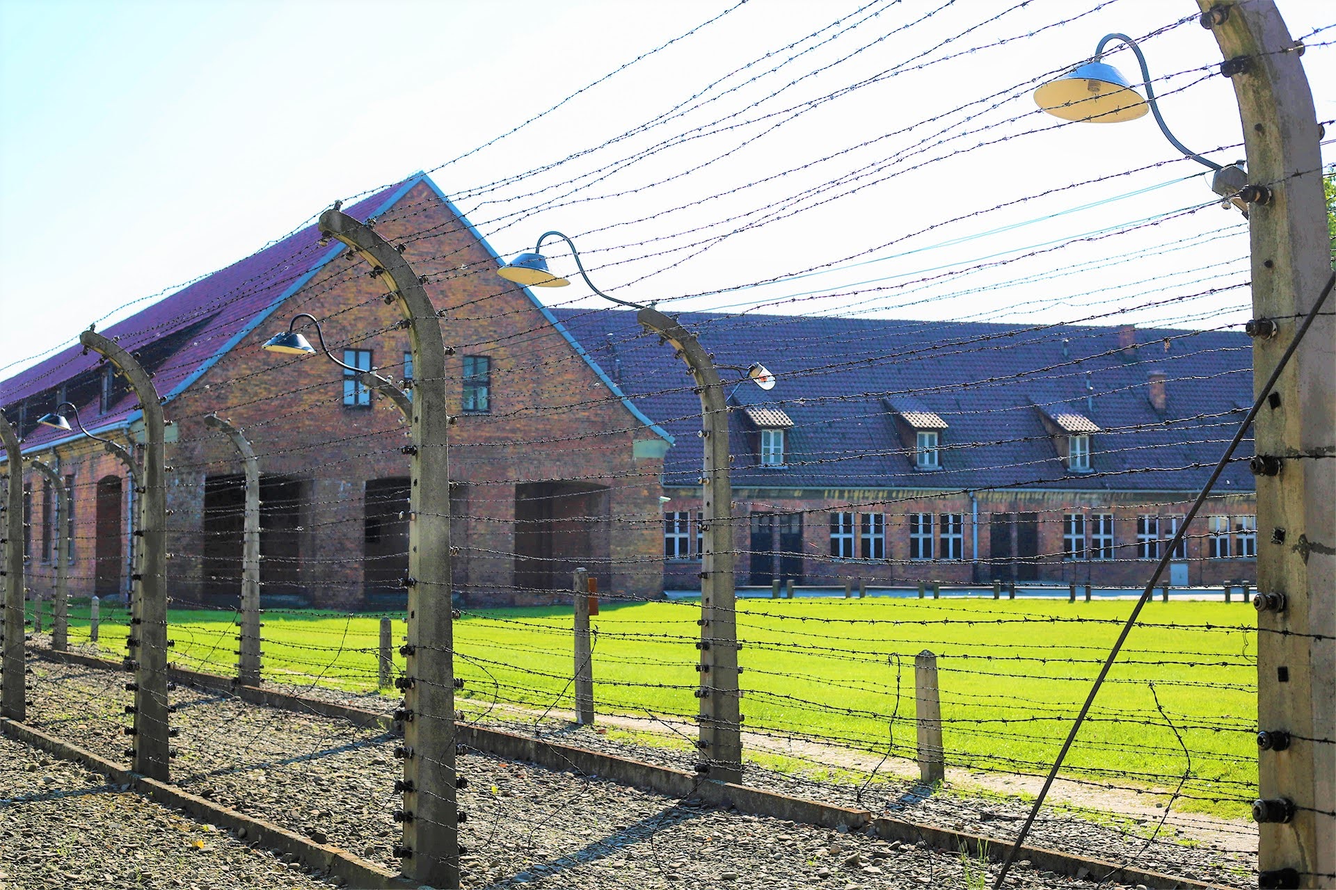 Electrified barbed-wire fence with barracks and lamps at Auschwitz